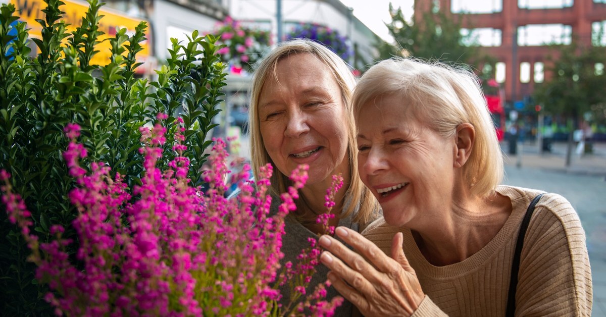 Two women looking at flowers and smiling.